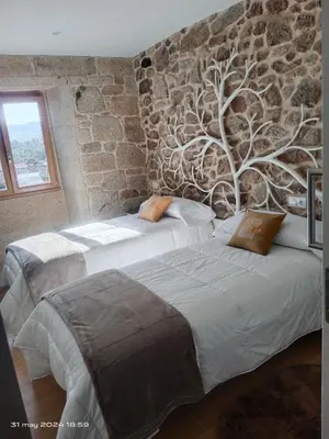 two beds in a room with a tree on the wall at Casa Desigual in Padrón