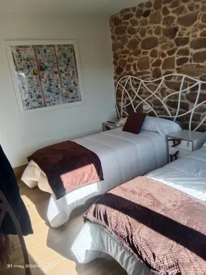 a bedroom with two beds and a stone wall at Casa Desigual in Padrón