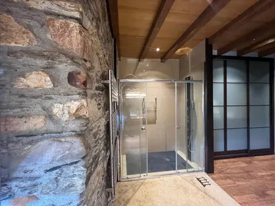 a glass shower in a room with a stone wall at Casa Ramona en Ribeira Sacra in Lugo