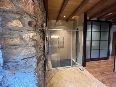 a glass shower in a room with a stone wall at Casa Ramona en Ribeira Sacra in Lugo