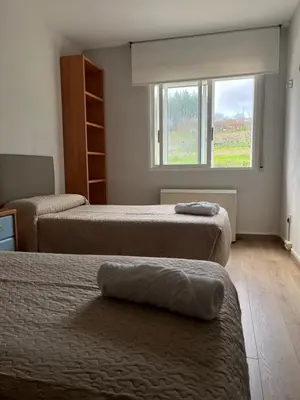 two beds in a room with a window and a bedvisor at Casa Vimar in Portomarin