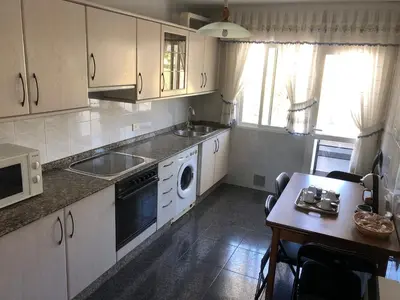 a kitchen with white cabinets and a sink and a dishwasher at Casa Vimar in Portomarin
