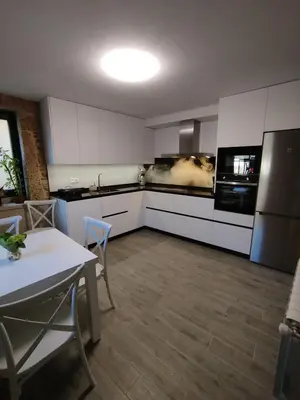 a kitchen with white cabinets and a table and a refrigerator at Casa Gallufe in Santiago de Compostela