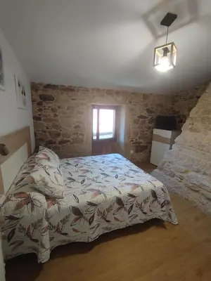 a bedroom with a bed and a stone wall at Casa Gallufe in Santiago de Compostela