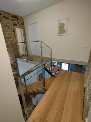 a room with a glass staircase and a stone wall at Casa Gallufe in Santiago de Compostela