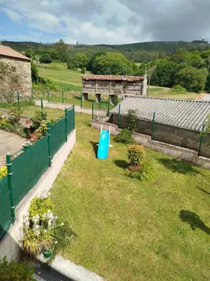 a garden with a blue trash can in the grass at Casa Gallufe in Santiago de Compostela