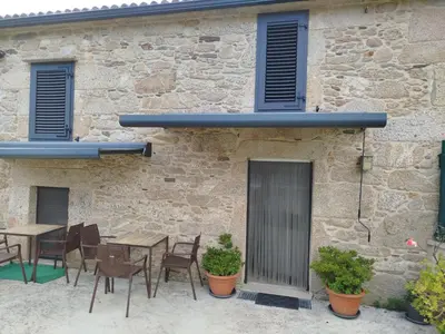 a patio with tables and chairs in front of a stone building at Casa Gallufe in Santiago de Compostela