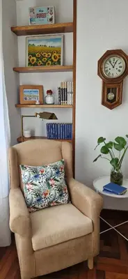 a chair with a pillow in a room with a clock at Apartamento Piñeirua in Ribadeo