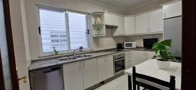 a kitchen with white cabinets and a sink and a window at Apartamento Piñeirua in Ribadeo