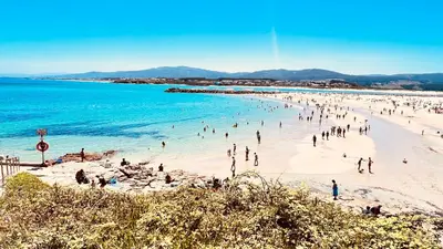 a group of people on a beach in the water at Apartamentos Terraza playa II in Foz