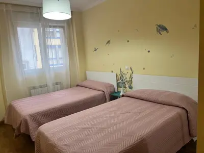 two beds in a room with pink sheets at Apartamentos Terraza playa II in Foz