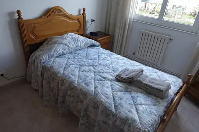 a bedroom with a bed with a blanket and a window at Carballeira house in Lago