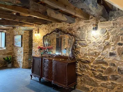 a stone room with a dresser and a mirror at CASA PEINADO in Boimorto