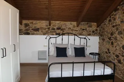 a bedroom with a metal bed in a stone wall at CASA PEINADO in Boimorto