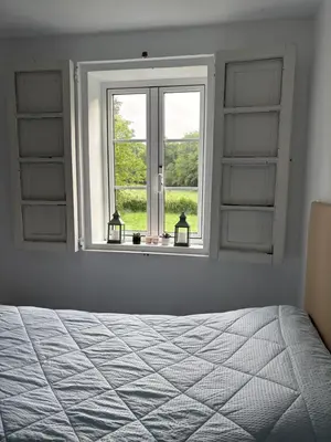 a bedroom with a window with a bed and two candles at A casa do Rio - The River House in Arzúa