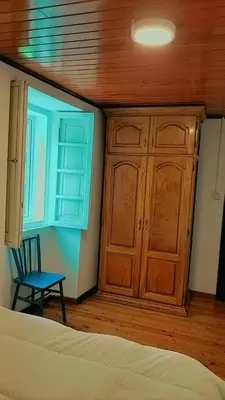a bedroom with a bed and a cabinet and a chair at A casa do Rio - The River House in Arzúa