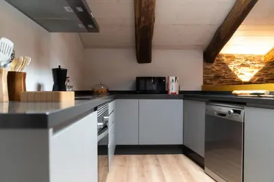 a kitchen with white cabinets and black counter tops at A Casa Dos Ratos in Quiroga