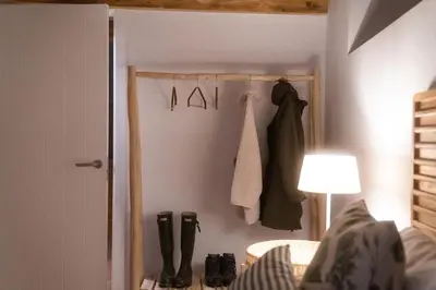 a bedroom with a closet with a robe and boots at A Casa Dos Ratos in Quiroga
