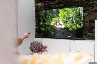 a person holding a remote control in front of a tv at A Casa Dos Ratos in Quiroga