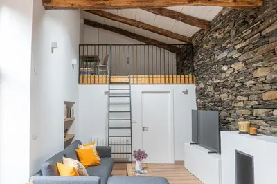 a living room with a loft conversion with a stone wall at A Casa Dos Ratos in Quiroga