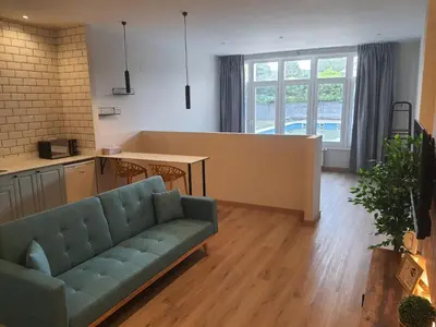 a living room with a couch and a kitchen at Pensión CREDENCIAL in Sarria