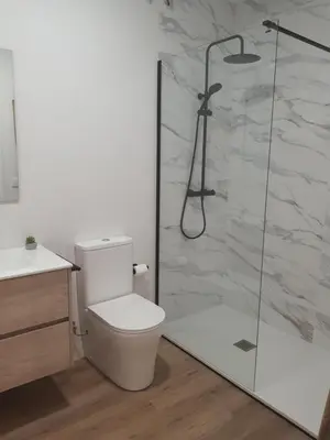 a bathroom with a toilet and a glass shower at Pensión CREDENCIAL in Sarria