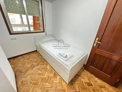 a bed in a room with a window and a door at O Rincón de Laly in Ourense
