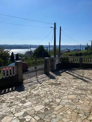 a fence with a stone patio with a view of the water at A casa de Roque 1 in Miño