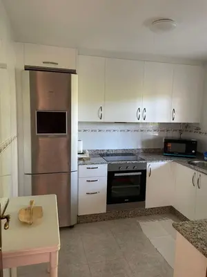 a kitchen with white cabinets and a stainless steel refrigerator at La Fincurri del Nando in A Coruña