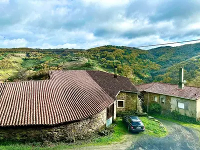 a car parked in front of a house with mountains at Lagar de Guxeva in Chantada