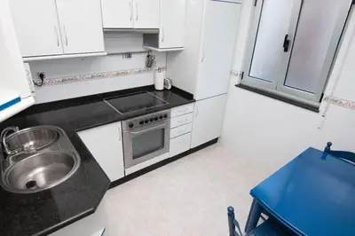 a kitchen with white cabinets and a sink and a stove at CASA Conchita in Ribadeo