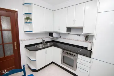 a small kitchen with white cabinets and a sink at CASA Conchita in Ribadeo