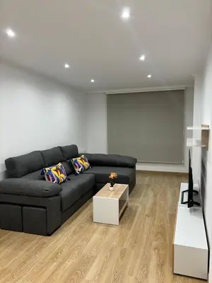a living room with a black couch and a screen at Alesamar A in Burela de Cabo