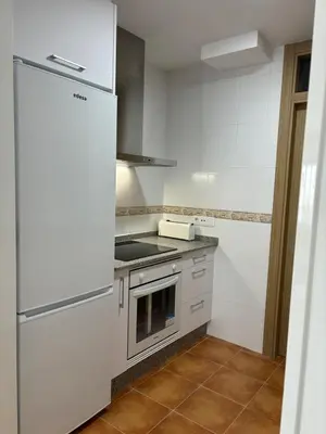 a white kitchen with a stove and a refrigerator at alesamar B in Burela de Cabo