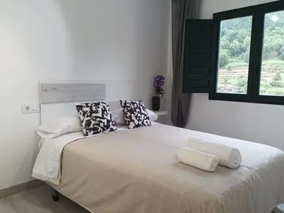 a bedroom with a white bed with pillows and a window at Casa dos avós in Ribadavia