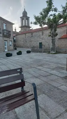 a bench sitting in front of a building with a tower at Casa dos avós in Ribadavia