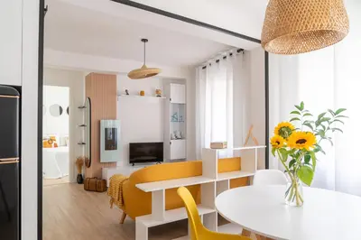 a kitchen and living room with a table and yellow chairs at Wanderlust Estudio in Ribadeo