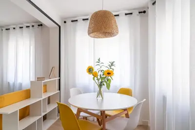 a white dining room with a white table and yellow chairs at Wanderlust Estudio in Ribadeo