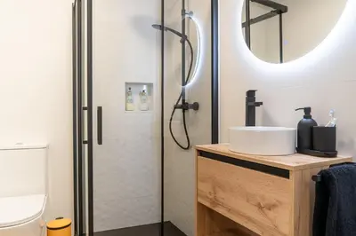a bathroom with a shower with a sink and a mirror at Wanderlust Estudio in Ribadeo