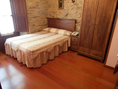 a bedroom with a bed and a wooden floor at Hostal Virgen de la Encina in Ponferrada