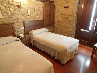 a bedroom with two beds and a stone wall at Hostal Virgen de la Encina in Ponferrada