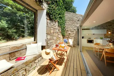 a house with a stone wall and a wooden deck at Casas do Sarela by Upper Luxury Housing in Santiago de Compostela