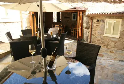 a table with two wine glasses and an umbrella at Casa Camino Turismo Rural in Palas de Rei
