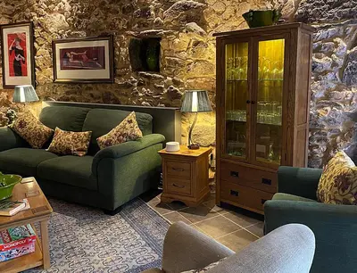 a living room with two couches and a stone wall at Casa Camino Turismo Rural in Palas de Rei