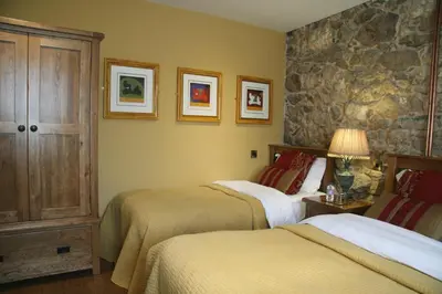 a bedroom with two beds and a stone wall at Casa Camino Turismo Rural in Palas de Rei