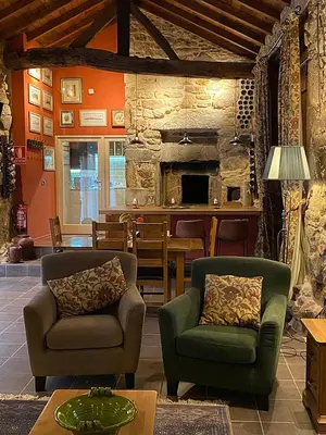 a living room with two chairs and a stone wall at Casa Camino Turismo Rural in Palas de Rei