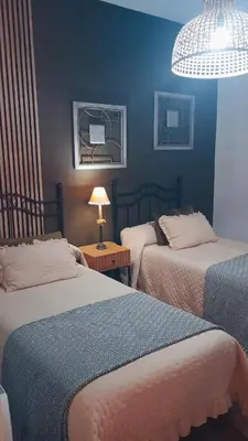 a bedroom with two beds and a lamp on a table at Mi Camino in Sarria
