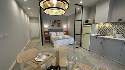 a room with a bed and a table and a kitchen at Apartamentos Paseo Colón in Foz