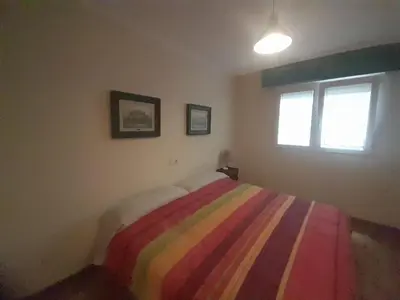 a bedroom with a bed with a colorful striped blanket at EnFOZ Con Piscina Parking y Playa a 100 metros in Foz
