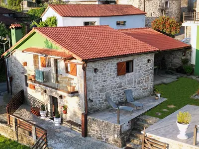 a small stone house with a red roof at Cozy Galician Stone Farmhouse with Fireplaces and Pool in Santo Tomé